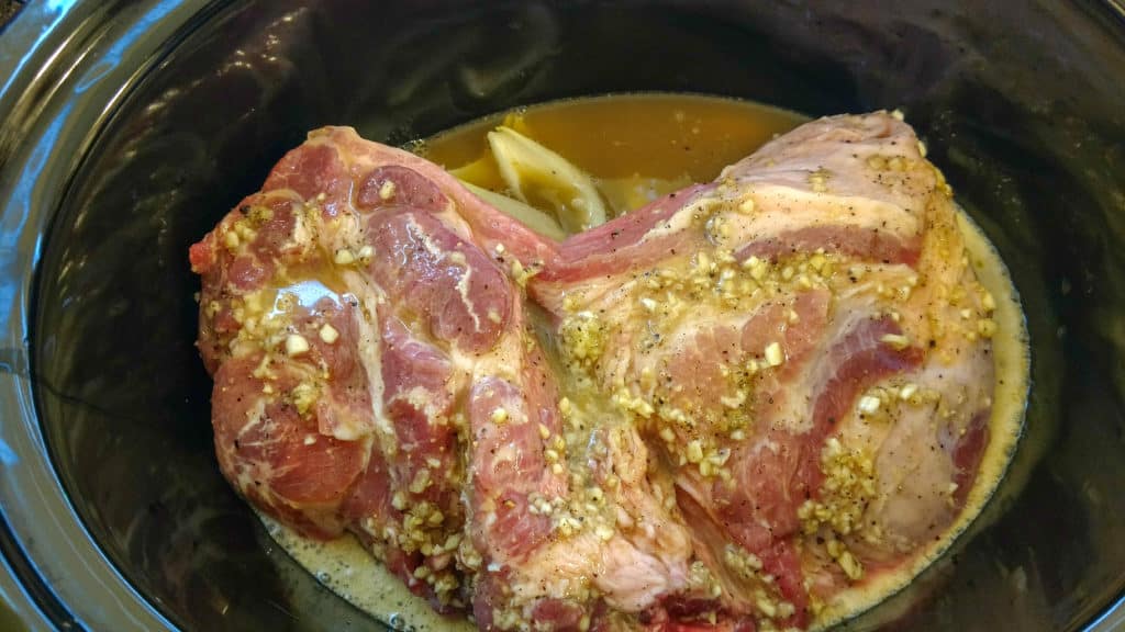 all ingredients for pork carnitas in a crockpot ready to start cooking