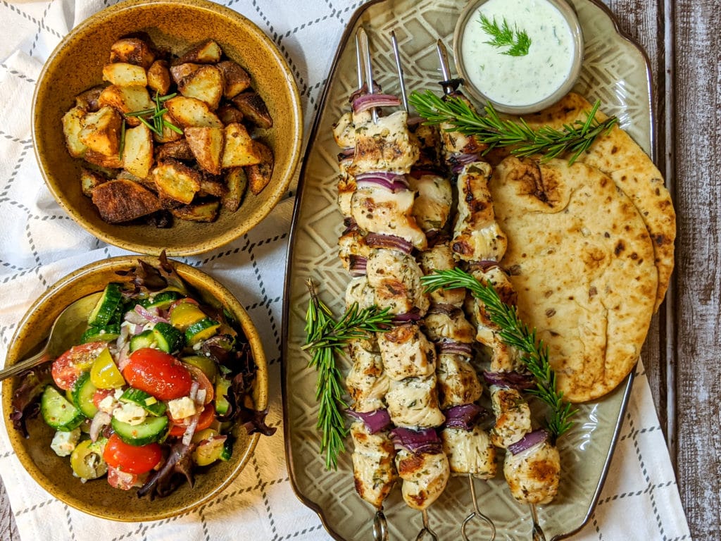 Chicken Souvlaki on a platter with greek salad and roasted potatoes on the side