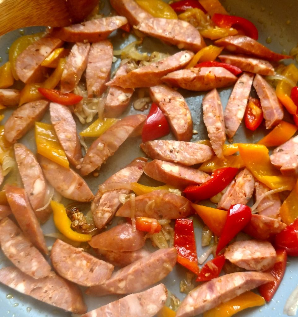 sausage, peppers and onions cooking in a pan