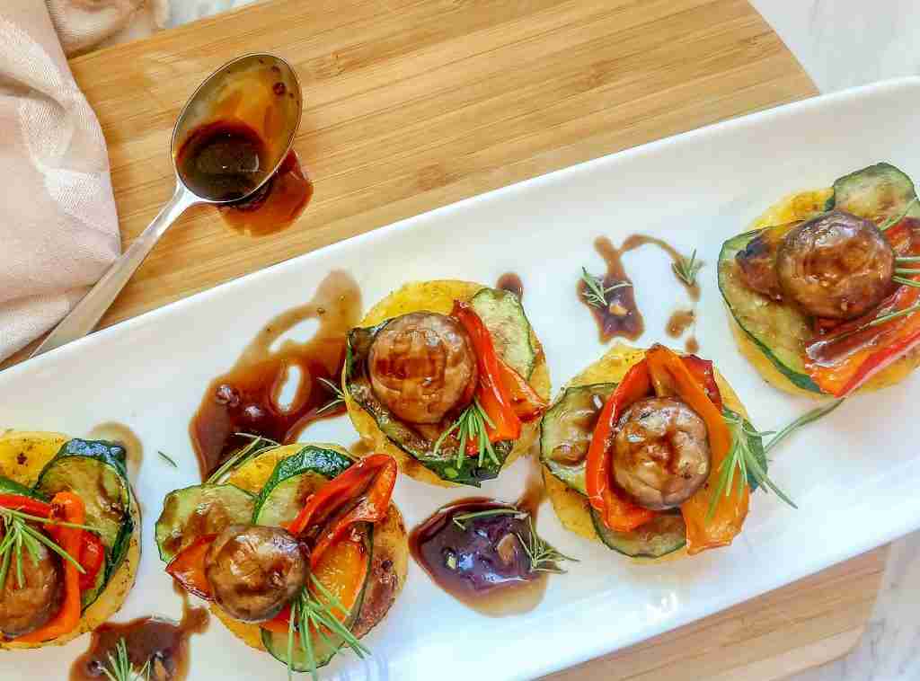 Grilled polenta and vegetable appetizers on a white platter