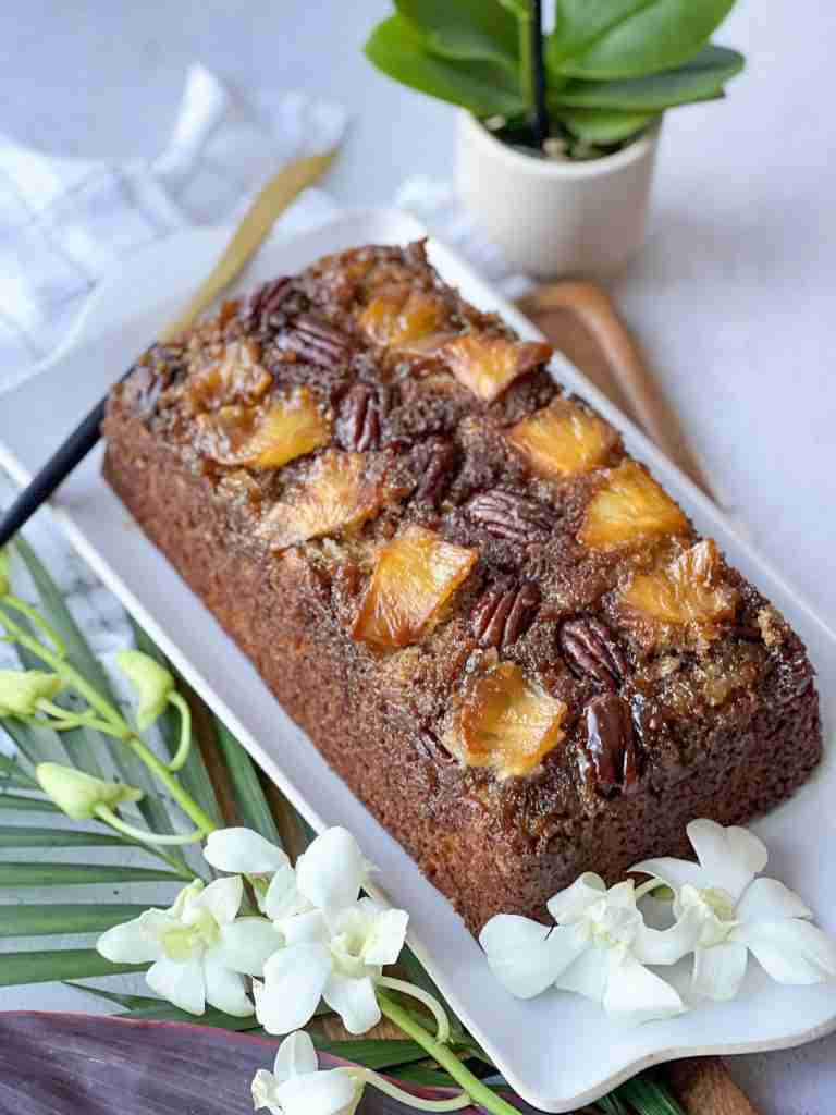 Pineapple banana bread on a white platter with white orchids