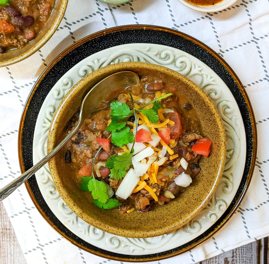 Chili in a bowl with garnish and a spoon
