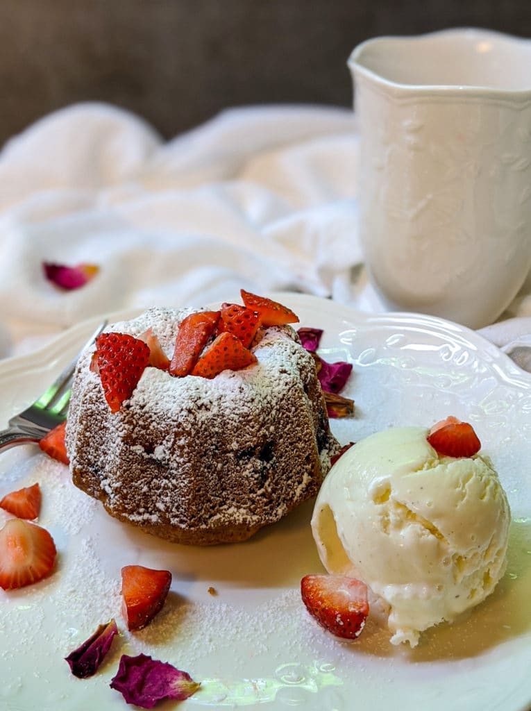 Strawberry tea cake on a plate with a scoop of vanilla ice cream