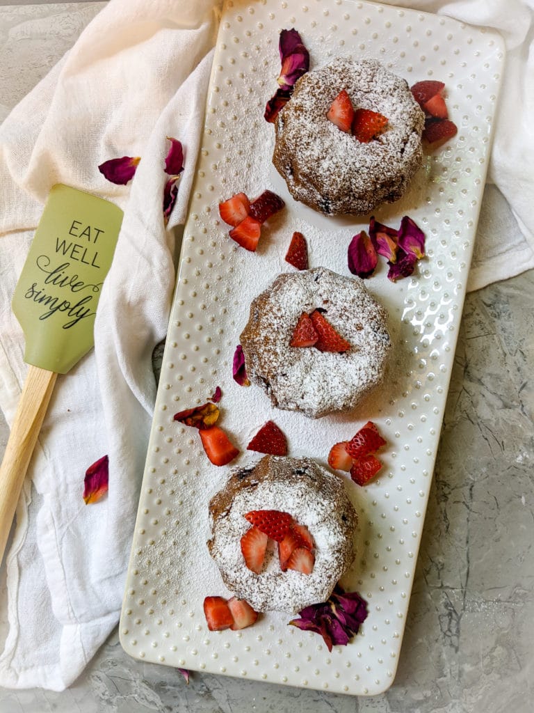 Strawberry Rose Tea Cakes on a white platter with strawberries and rose petals