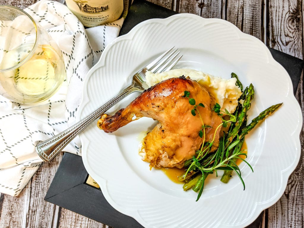 lemon roasted chicken on a white plate with mashed potatoes and asparagus
