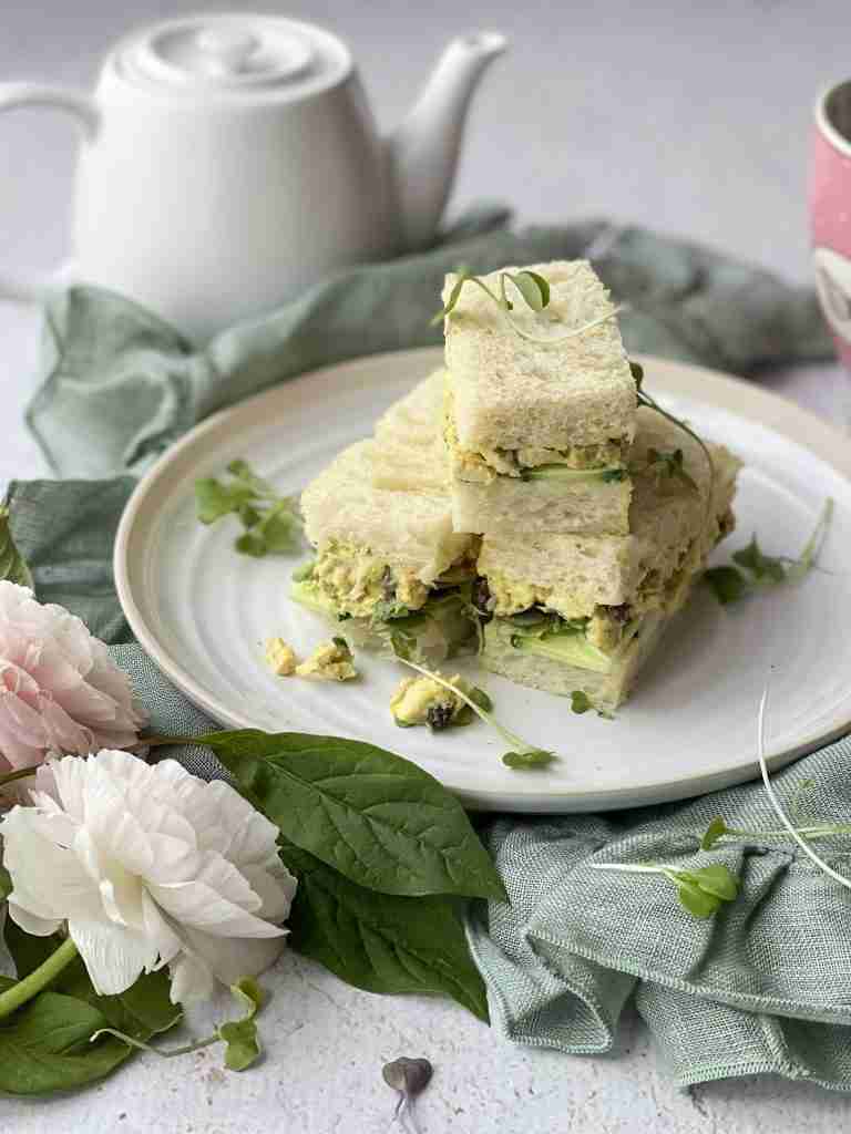 coronation chicken sandwiches stacked on a white plate