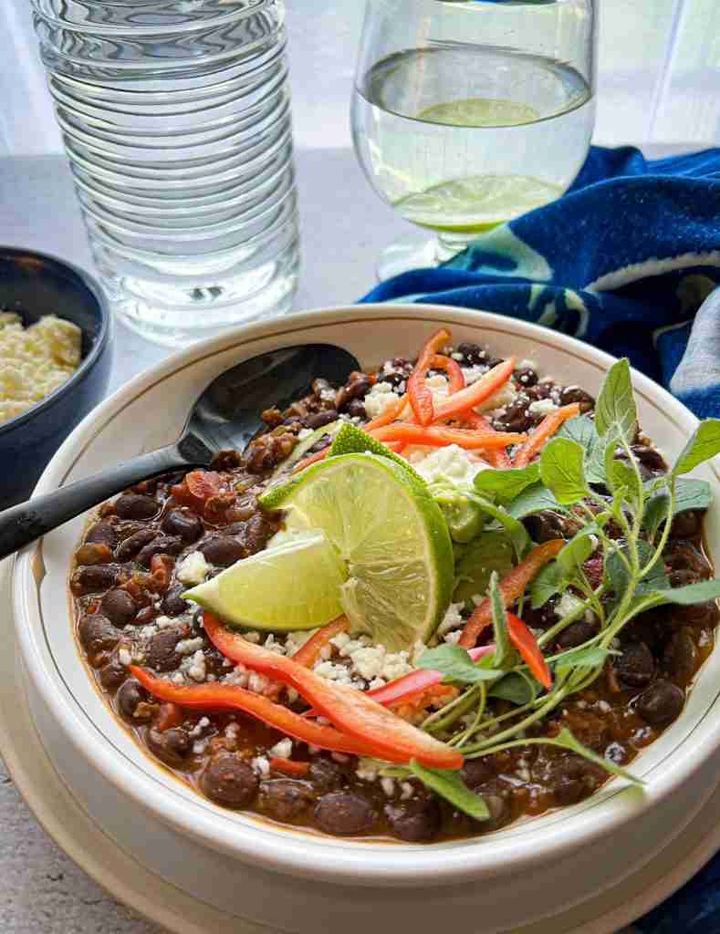 Black bean chili with chorizo in a white bowl with a spoon