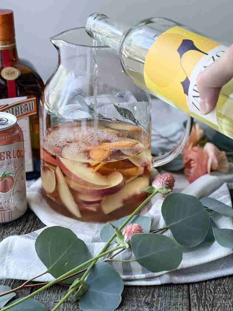 Wine poring into a pitcher of fruit